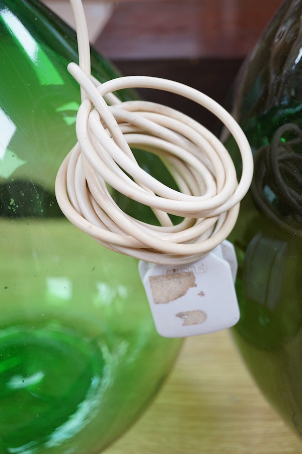 Two green glass carboys, one converted to a lamp, 58cm high overall. Condition - good, untested